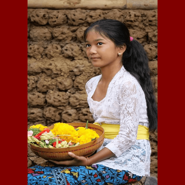 Jeune fille avec tenue traditionnelle balinaise qui à des offrandes dans les mains